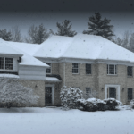 Surburban house in Vermont with roof asphalt shingles covered in snow from storm.