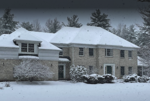 Surburban house in Vermont with roof asphalt shingles covered in snow from storm.