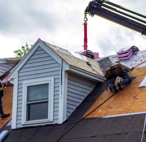 Roofing contractors doing spring roof work and roof repairs on suburban home.