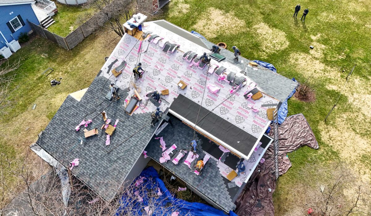 Roofing contractors putting roofing underlayment in place for roof protection.