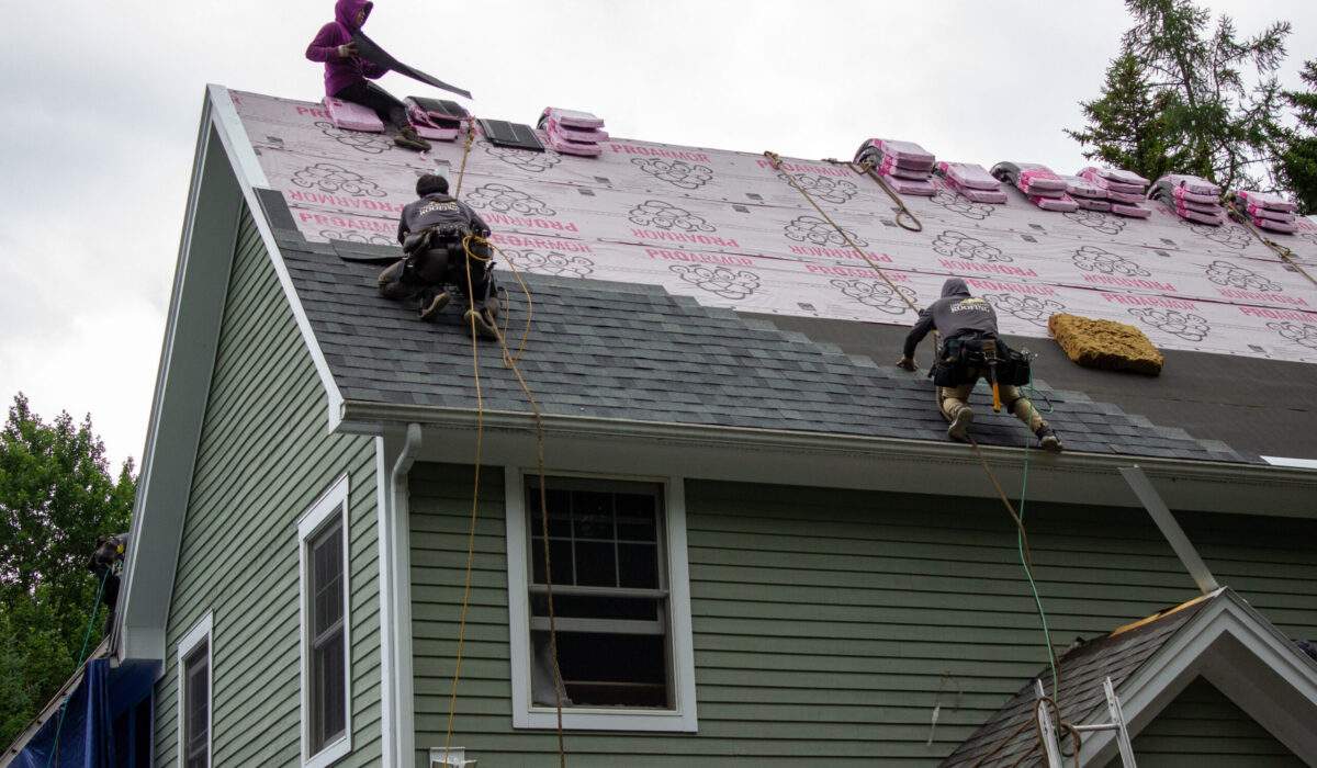 Roofing contractors in Vermont working on roofing upgrades to asphalt shingles roof improve home market value.
