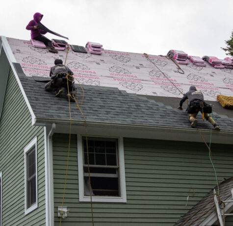 Roofing contractors in Vermont working on roofing upgrades to asphalt shingles roof improve home market value.