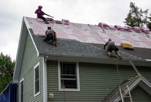Roofing contractors in Vermont working on roofing upgrades to asphalt shingles roof improve home market value.