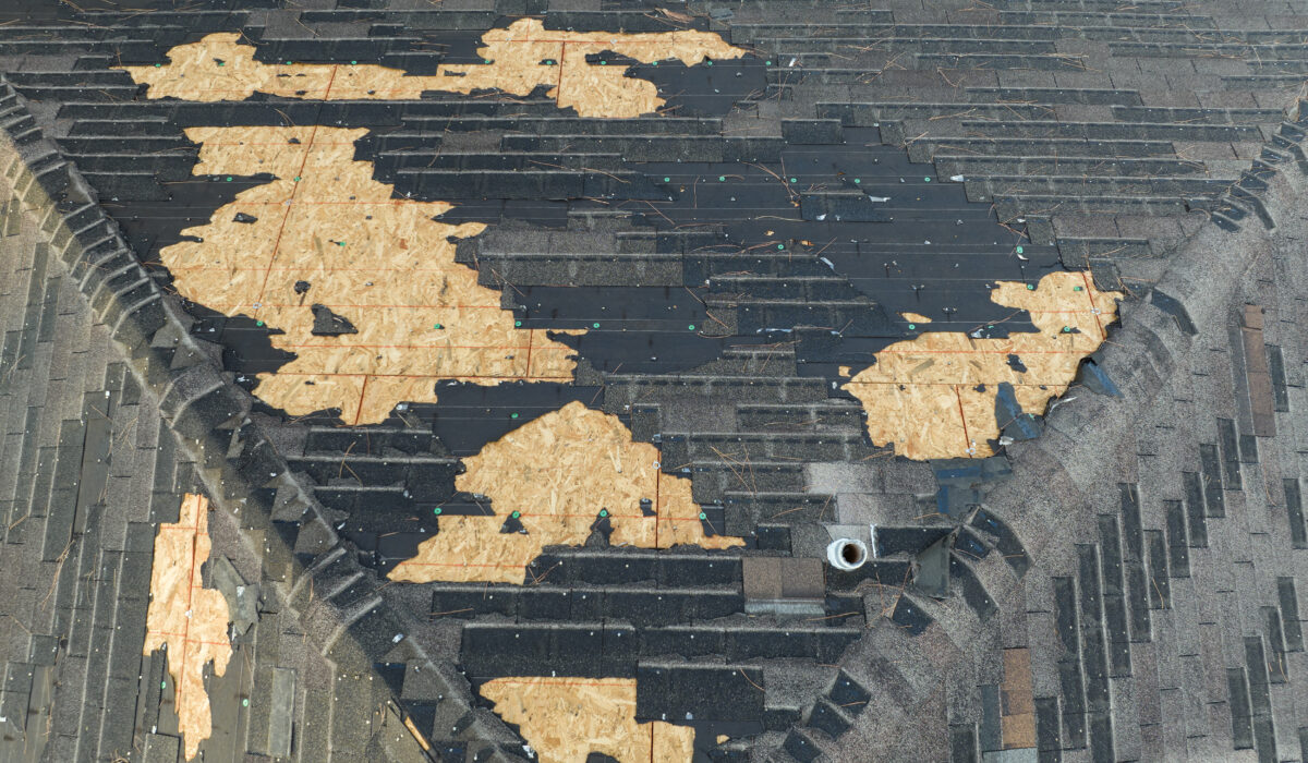 Ruined rooftop with storm damage to asphalt shingles.
