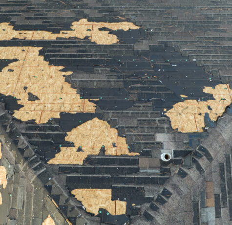Ruined rooftop with storm damage to asphalt shingles.
