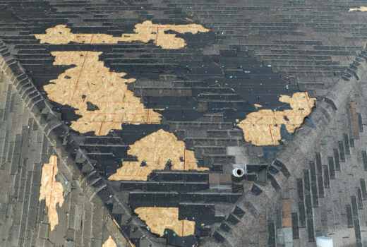 Ruined rooftop with storm damage to asphalt shingles.