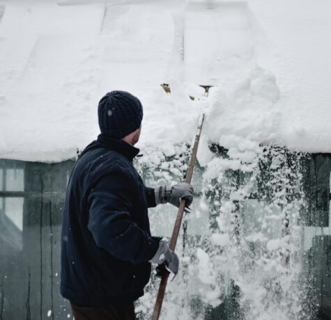 Vermont homeowner removing snow from roof to prevent winter roofing problems.